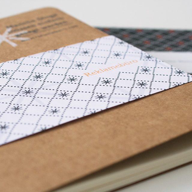 Ein Notizbuch mit einer Banderole liegt auf einer Karte mit einem durchgängigen Muster
